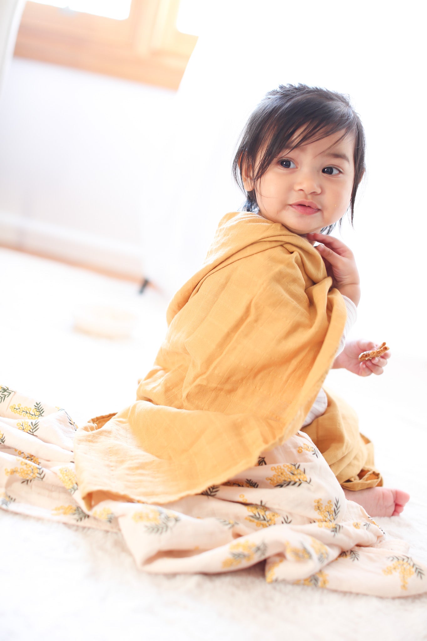 Toddler girl wearing nectar yellow swaddle blanket as a cape